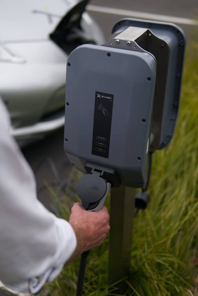 Hand steekt stekker in elektrische lader
