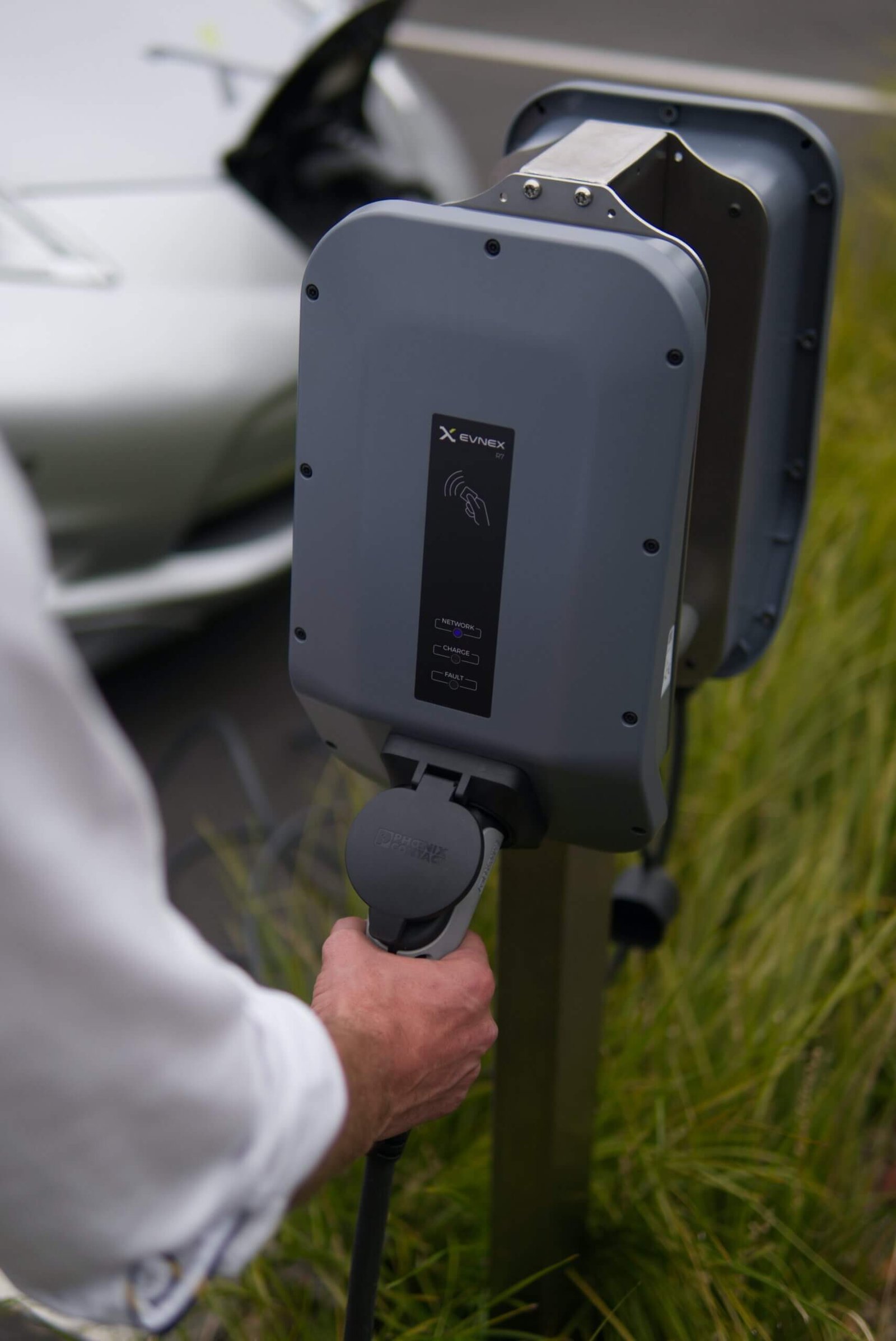 Hand steekt stekker in elektrische lader